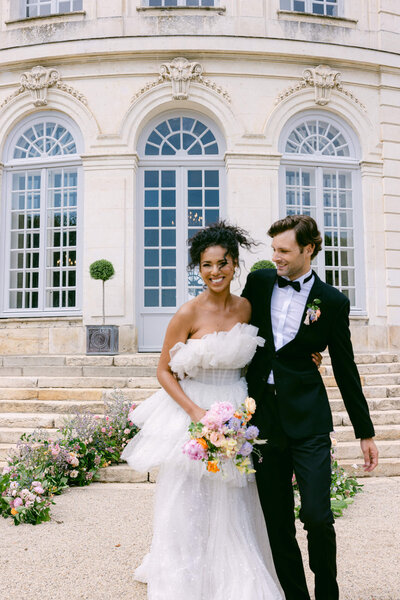 candid iage of the wedding couple smiling and hugging each other as they walk down the aisle together after saying I Do with chateau du grand luce in the background