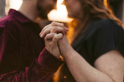 man and woman holding hands while woman shows off engagement ring