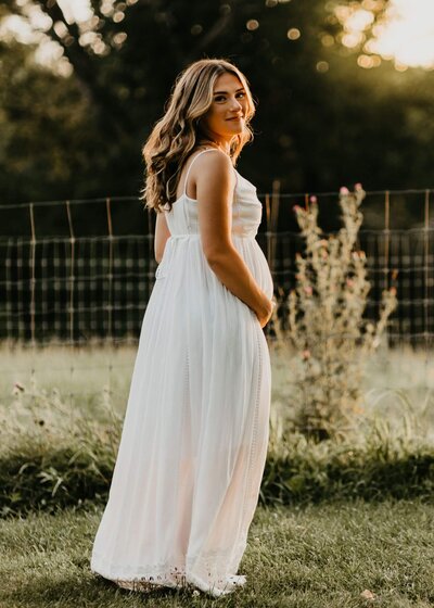 Pregnant mother standing in a field of flowers at golden hour.  Photographed by Pittsburgh newborn photographer Tracy Miller