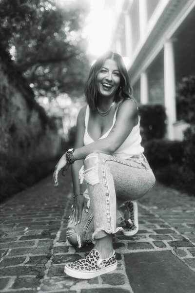 Black and white photo of woman laughing wearing white top and jeans