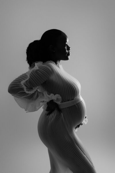 Artistic maternity portrait showcasing pregnant silhouette in modern dress by Austin maternity photographer with professional studio lighting