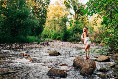 Outdoor boudoir woman in lingerie standing on boulder in Rattlesnake River, Missoula