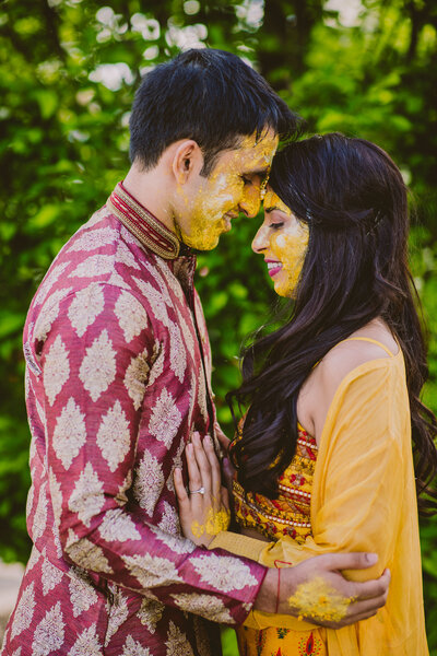 An indian bride and groom sharing a moment with haldi turmeric on their faces