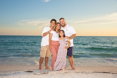 cute little family of four on the beach at sunset