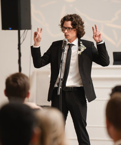 Wedding guests laugh while best man delivers a funny wedding speech.