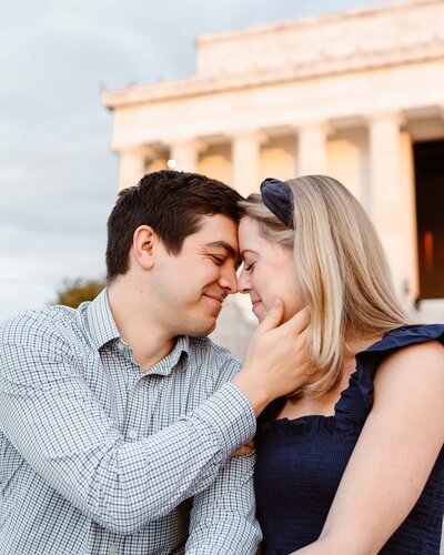 Man and woman almost kiss while sitting in front of the Lincoln Memorial during their Washington DC Engagement Session