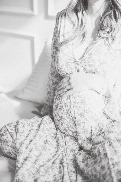 black and white image of mama resting her hand on her pregnant belly