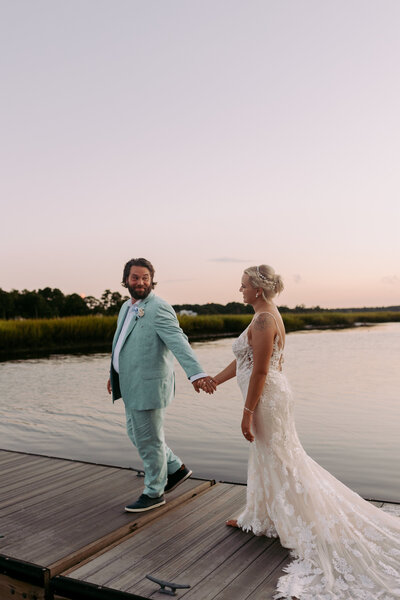 Bride and groom holding their hand while walking together at sunset on the evening of their wedding 