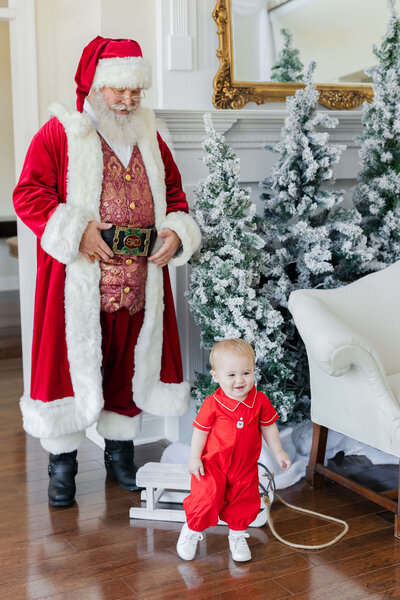 Baby standing with santa in indoor christmas setup