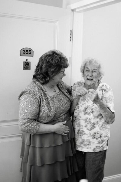 Older women smiling while one has their arm around the other.