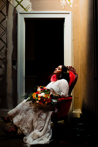 A bride sitting in a red chair looking up towards a skylight at the Ford Mansion in Toledo Ohio