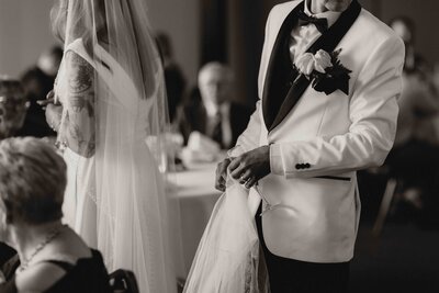 Groom holding train of brides dress, with their faces out of frame.