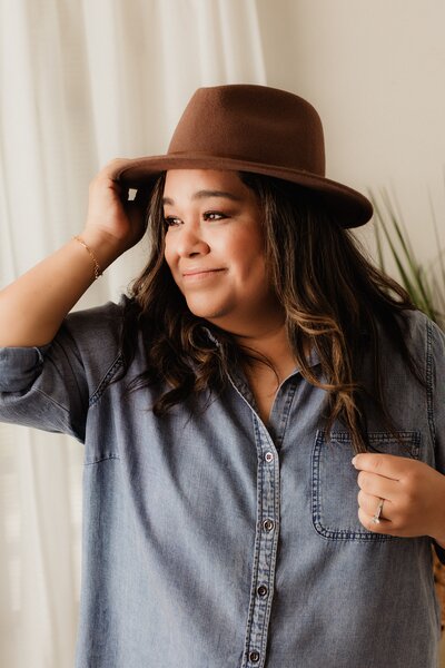 Inland Empire Newborn Photographer. Vanessa Kuns smiling off to the side with hand on hat. 