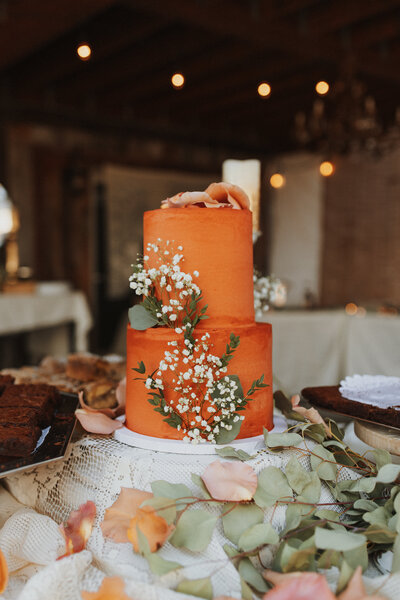 A wedding cake that is burnt orange and has white flowers on it