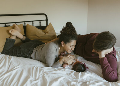 man and woman laying down and looking at baby