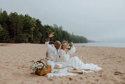 bride and groom having a picnic on a beach on madeline island. 