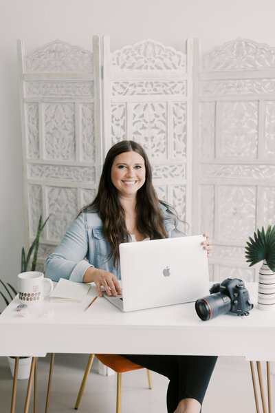 Leah Rife, South Bend photographer, working on her laptop in a bright, modern studio space.