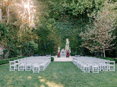 White reception tent draped with greenery with guests sitting at tables underneath