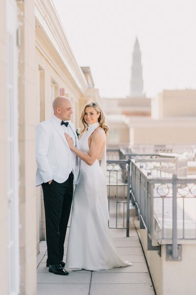 timeless wedding photo of bride and groom stand by each other on a hotel deck WITH Washington D.C. monument in the back