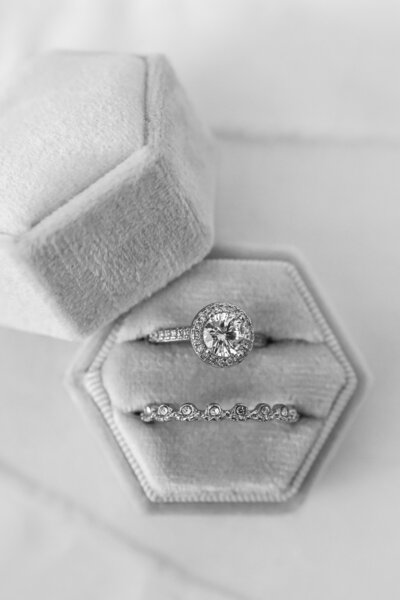 An engagement ring and wedding band in a small grey ring box.