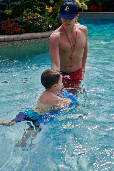 A lifeguard patiently teaching a boy how to swim, promoting water safety and skill development