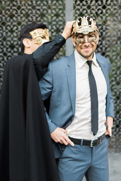 Groomsman ties a mask onto groom on his wedding day