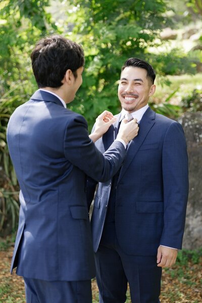 A person helping a newlywed adjust their tie 