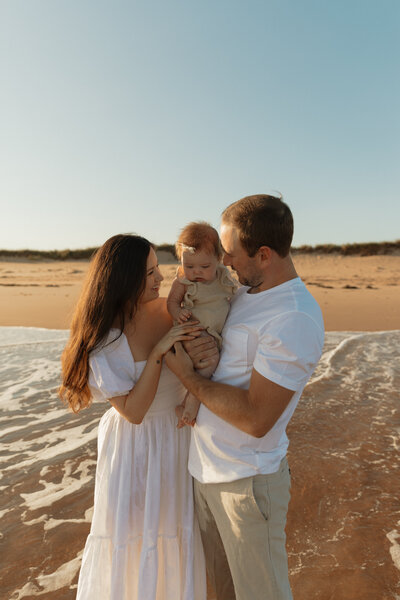 mom and dad holding baby on beach for family photos in pei