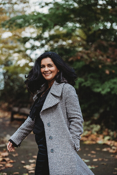 Personal brand image of confident female entrepreneur walking in autumn leaves wearing smart coat