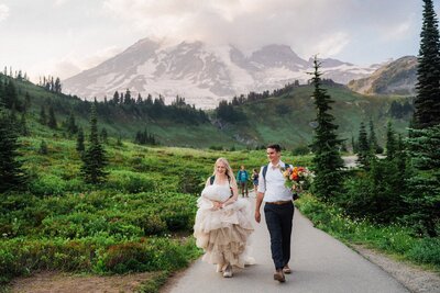 A couple hiking with Mt Rainier in the background after saying their vows for during sunset.