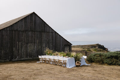 person in a dress shirt and vest kisses their partner's hand while they sit at the head table during their wedding