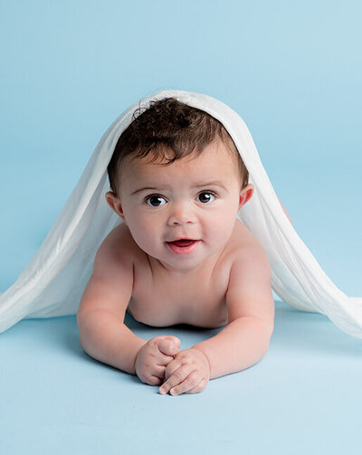 Baby lying on a blue floor with a white cloth.