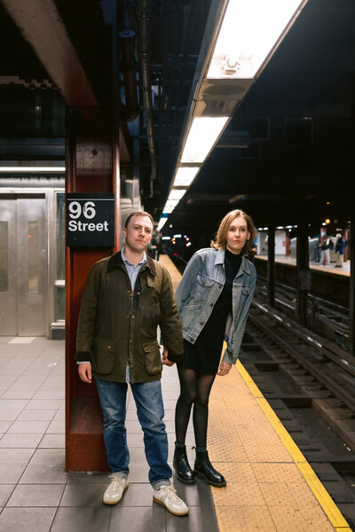 couple holding hands on a subway platform looking for an incoming subway in new york city