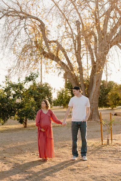 Couple holding hands and looking at her baby bump