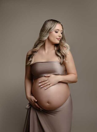Maternity photoshoot of Mom holding her baby bump and soaking in this milestone moment. Photo taken by Jenni Nikki net at Atlanta photography studio in Woodstock, GA.