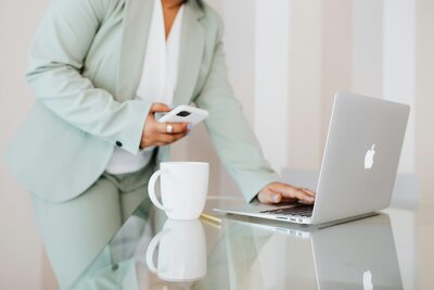 Person holding phone using laptop