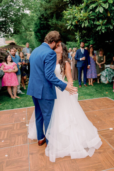 A newlywed couple kissing during their first dance at their reception 