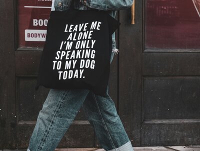 A person wearing a black t-shirt with text "Leave me alone, I’m only speaking to my dog today.