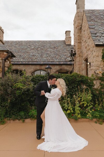 bride and groom kissing in front of their timeless, european inspired wedding at Cherokee Ranch and Castle 