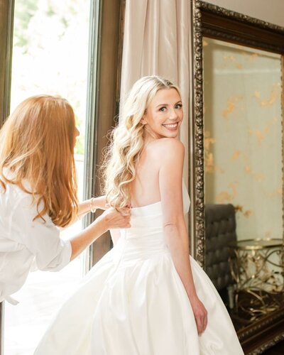 Lucy's mom zipping up her wedding dress in the bridal suite at Blackstone Rivers Ranch wedding venue.