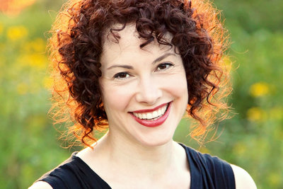 Close up image of smiling woman with red, curly hair.