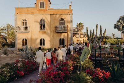 Guests walk back to the villa from the beach wearing red and beige