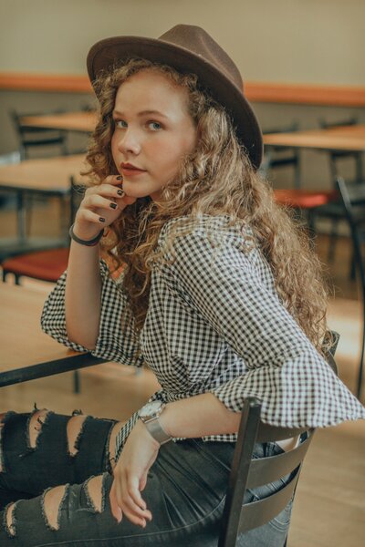 A teenage girl with curly hair and a hat turns to look at the camera