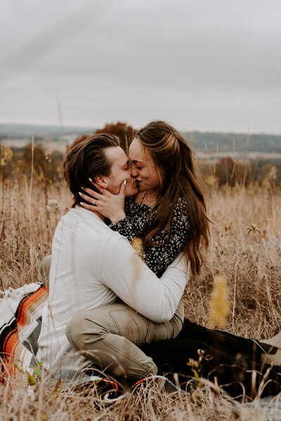 couple on blanket in field kissing