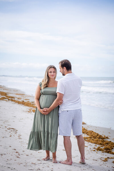 A couple takes maternity photos while on the beach