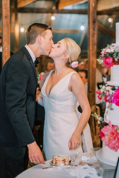 Flash photo of bride and groom kissing beside their wedding cake