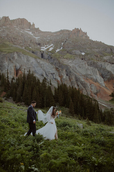 Bride and groom walk through the Colorado mountains