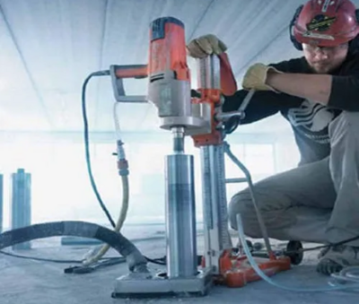 An operator in a hard hat coring through concrete slab creating holes ranging from 1 to 22 inches.