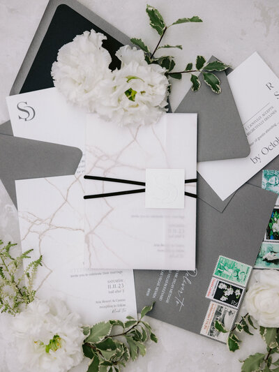Flat lay of luxe black, white, and gold foil wedding invitation suite and wedding details