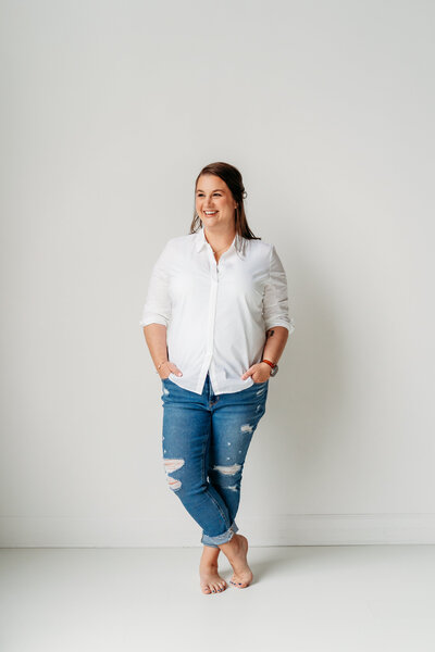 Woman standing with legs crossed and hands in pocket.